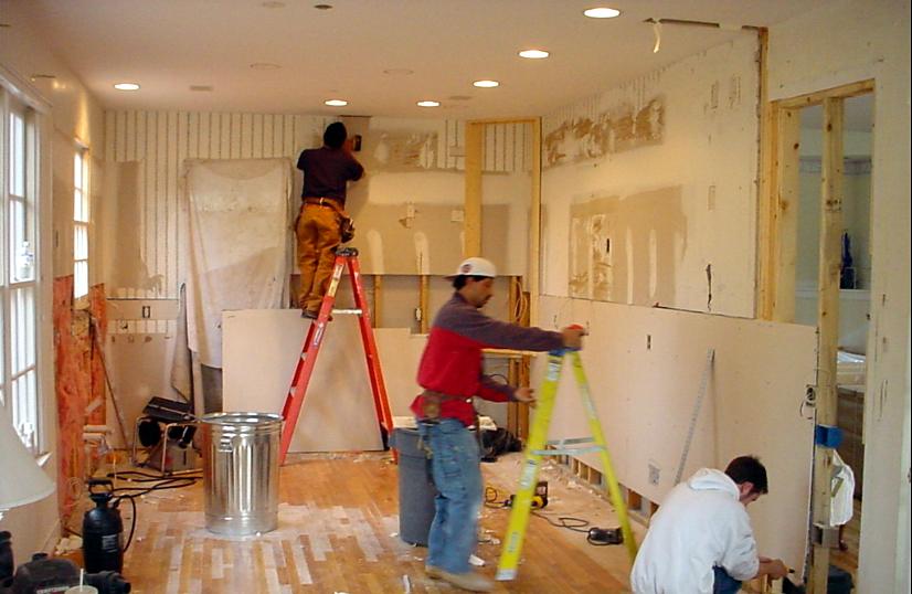 Carpenters framing and hanging drywall mid-renovation