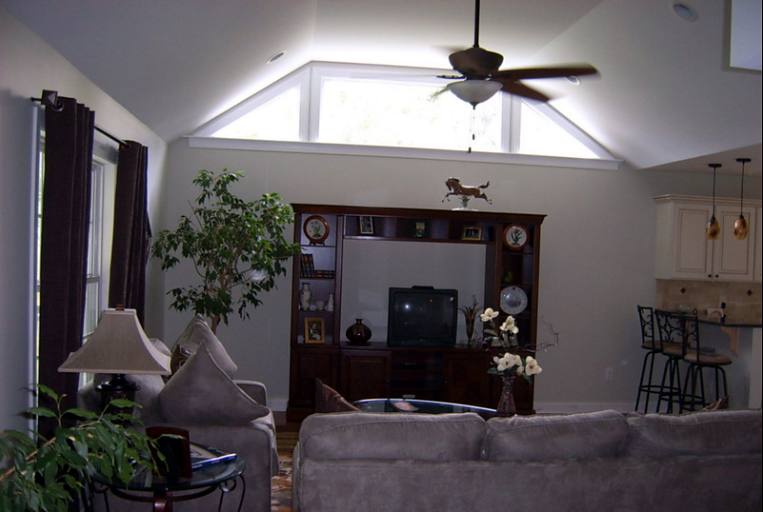 Living room with a vaulted ceiling, gable window and ceiling fan