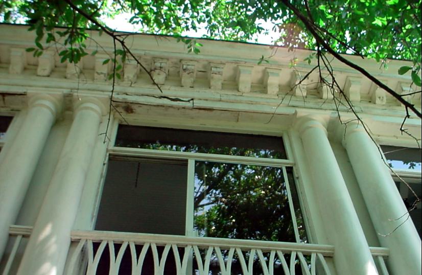 Porch with white columns and a decorative railing